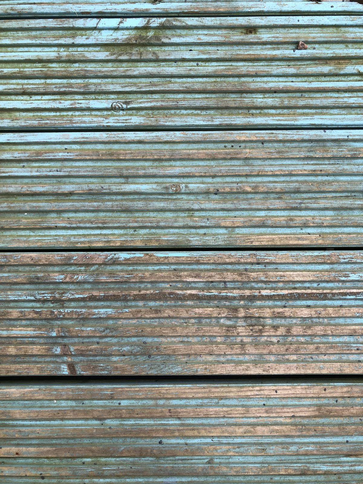 Weathered deck boards with peeling finish showing need for refinishing